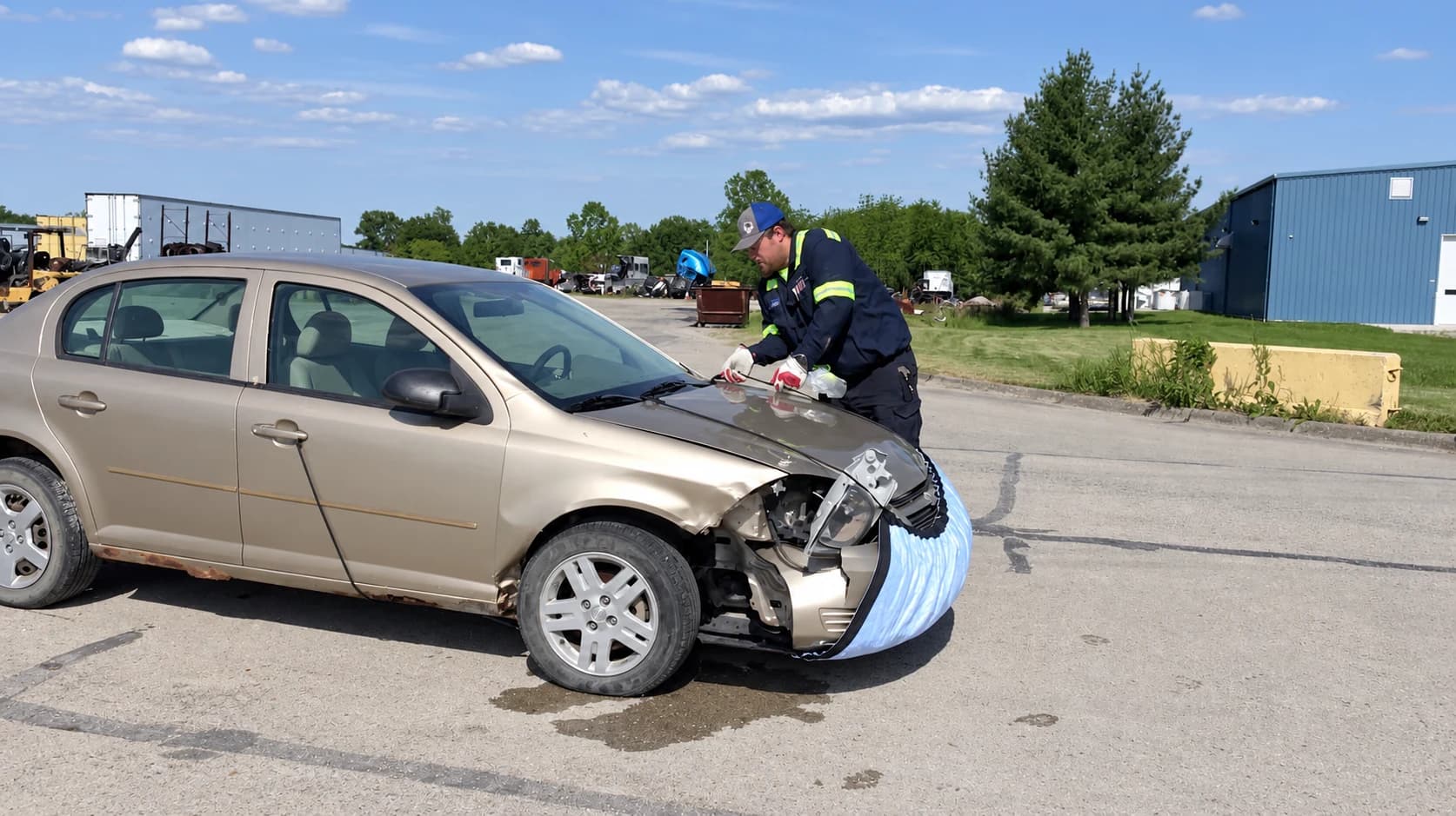 Technician securing Spill Diaper around the damaged front of a sedan