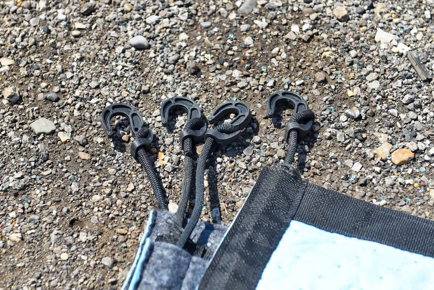 Close view of the four separate black plastic hooks on the Spill Diaper cords